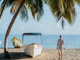 A man standing on a beach next to a boat